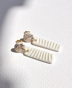 Pendientes colgantes blancos con textura dorada y base rectangular blanca con relieve